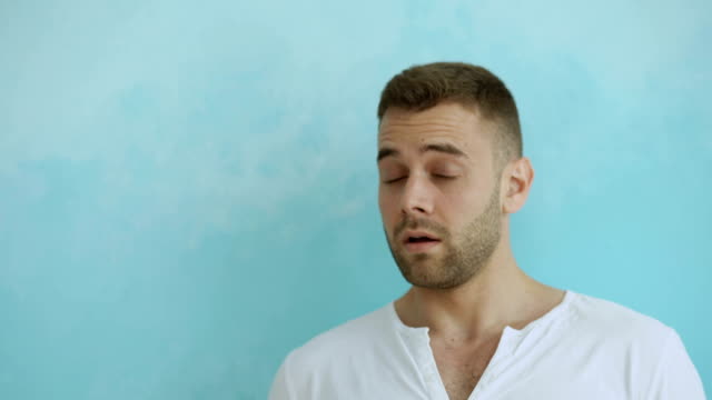 Portrait-of-young-man-actively-surprising-and-wondering-looking-into-camera-on-blue-background