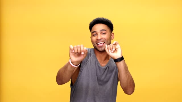Young-happy-african-man-dancing-over-yellow-background.