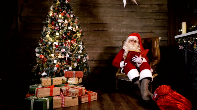 Libro-de-lectura-de-Papá-Noel-junto-a-árbol-de-Navidad