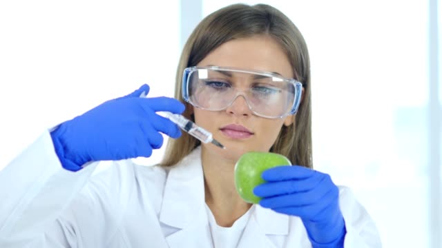 Weiblichen-Arzt,-Wissenschaftler,-die-Injektion-von-Apple-mit-chemischen-Reaktion