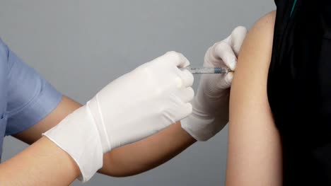 Inyección-contra-la-gripe-al-brazo-del-paciente-el-doctor