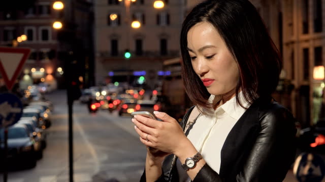 Mujer-de-negocios-asiática-se-centró-en-mecanografiar-en-el-smartphone,-noche-de-la-ciudad