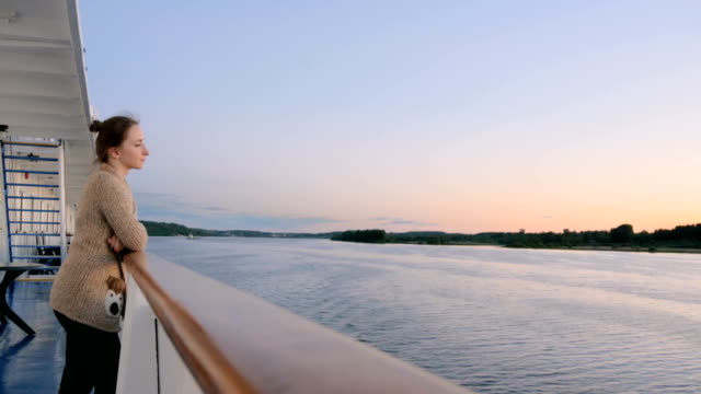 Frau,-die-Landschaft-vom-Deck-des-Kreuzfahrtschiffes-nach-Sonnenuntergang-bewundern