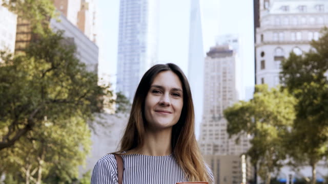 Porträt-des-jungen-glücklich-Geschäftsfrau,-stehen-im-Park-des-Finanzplatzes-New-York,-USA-und-Unterlagen