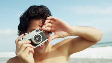 Handsome-ethnic-male-using-retro-camera-beach-vacation