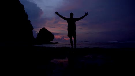 Man-rising-hands-up-and-enjoying-the-moment-at-sunrise