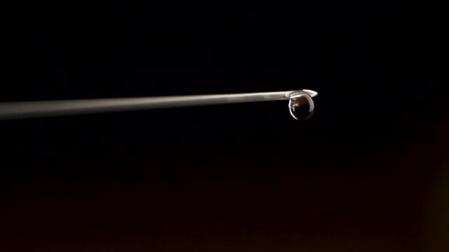 Medical-injection-syringe-with-drop-falling-from-the-needle-shallow-depth-of-field.-Drop-falling-from-needle.-Close-up-of-Hypodermic-syringe-falling-drop,-macro
