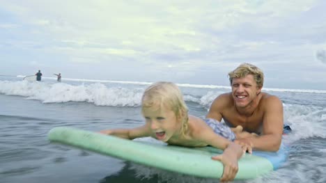 Vater-und-Sohn-schwimmen-auf-Surfbrett-im-Ozean