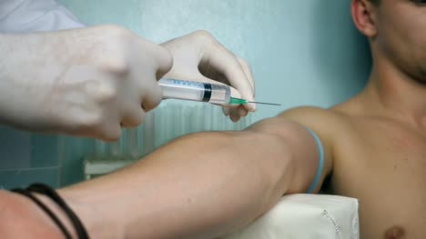 Male-hand-of-doctor-injects-a-syringe-into-a-vein-of-patient.-Arm-of-medic-making-injection-vaccine-to-ill-man-at-hospital.-Close-up-Side-view