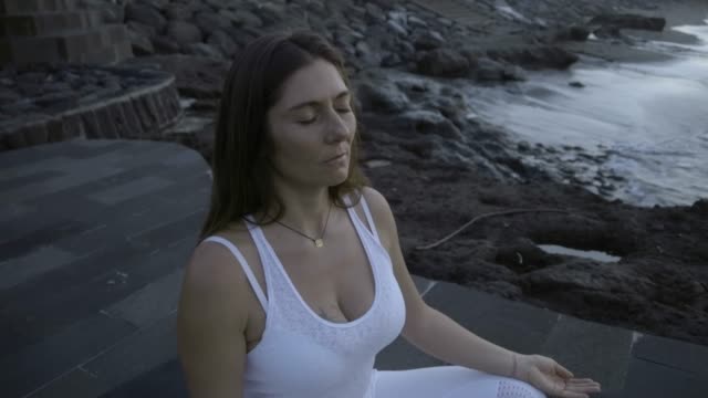 Frau,-meditieren-in-Lotus-Pose-auf-Küste