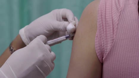 Doctor-holding-syringe-for-vaccination-to-upper-arm-of-patient