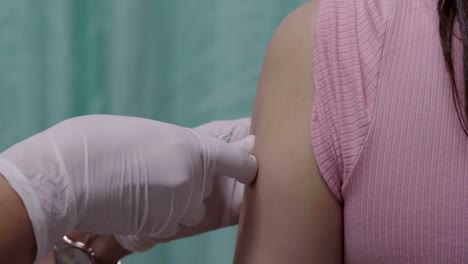 Arzt-Holding-Spritze-für-die-Impfung-zu-Oberarm-des-Patienten