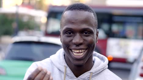 glücklich-und-lächelnd-junger-afrikanischer-Mann-im-Gespräch-mit-der-Kamera-auf-der-Straße