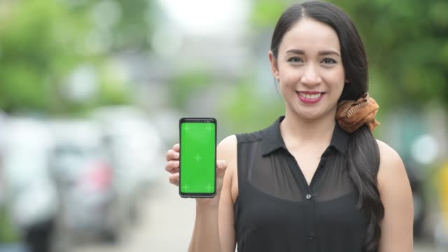 Junge-glücklich-schöne-asiatische-geschäftsfrau-zeigt-Telefon-in-der-Straßen-Natur