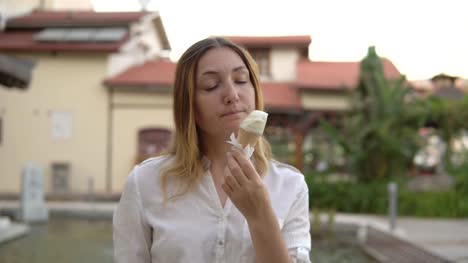 Porträt-von-schöne-positive-junge-Frau,-die-auf-Grund-von-Palmen-Eis-essen