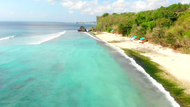 Playa-y-mar-color-turquesa-con-olas-en-Bali,-video-aéreo.