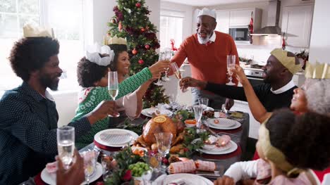 Black-grandfather-standing-to-make-a-speech-and-a-toast-at-the-head-of-the-family-Christmas-dinner-table,-front-view
