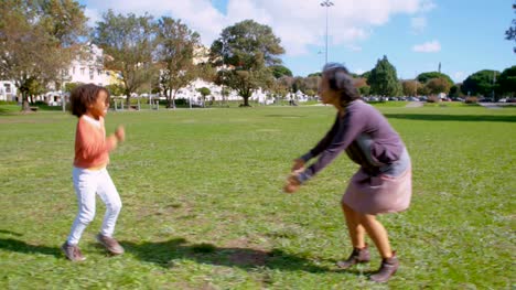 Fröhliche-afrikanische-amerikanische-Tochter-läuft,-asiatische-Mutter-im-park