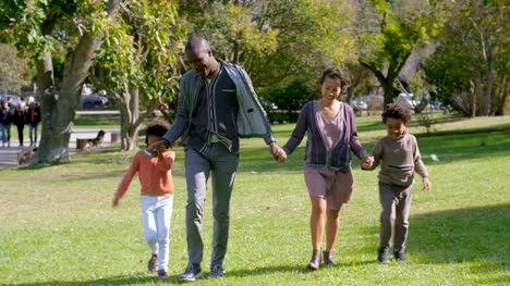 Smiling-Multiethnic-parents-and-kids-holding-hands-and-walking