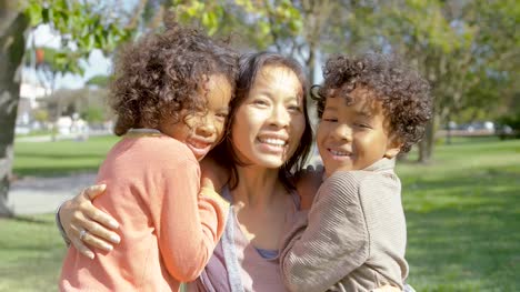 Happy-African-American-kids-kissing-and-hugging-Asian-mother