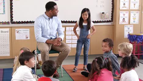 Asian-schoolgirl-standing-with-teacher-in-front-of-class