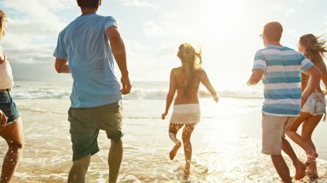 Group-of-friends-having-fun-walking-down-the-beach-at-sunset