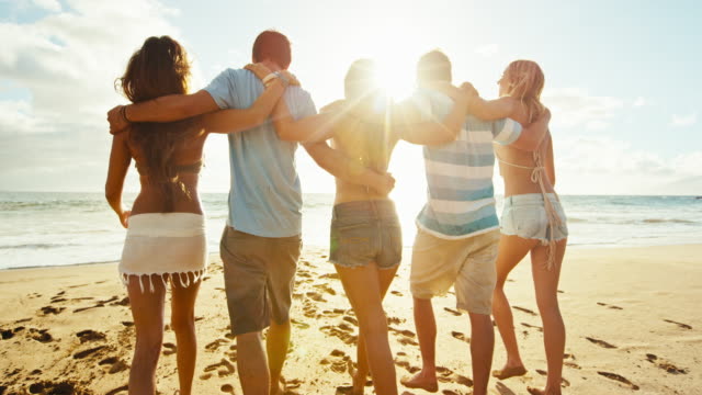 Gruppe-von-Freunden-Spaß-einem-Strandspaziergang-bei-Sonnenuntergang