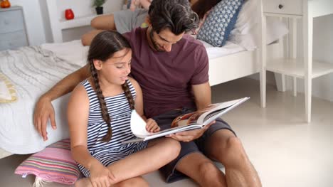 Vater-und-Tochter-sitzen-im-Schlafsaal-Lesebuch-zusammen