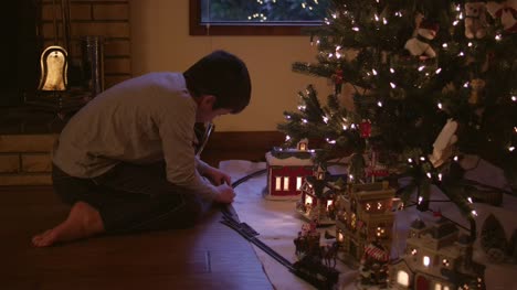 Niño-Armando-tren-pistas-delante-del-árbol-de-Navidad