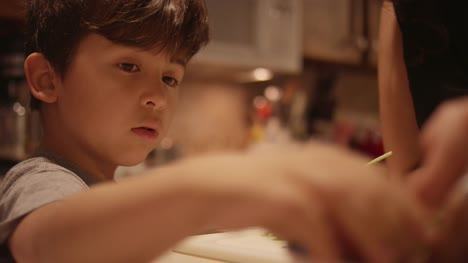 A-little-boy-helping-his-mom-prepare-food-in-the-kitchen,-close-up