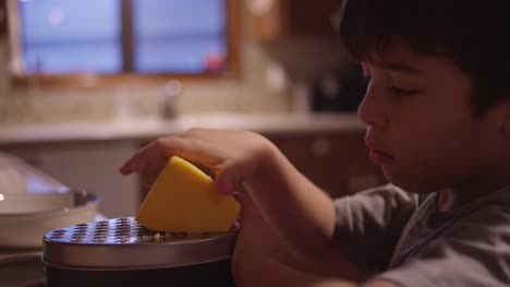 Ein-kleiner-Junge-Schreddern-Käse-in-der-Küche