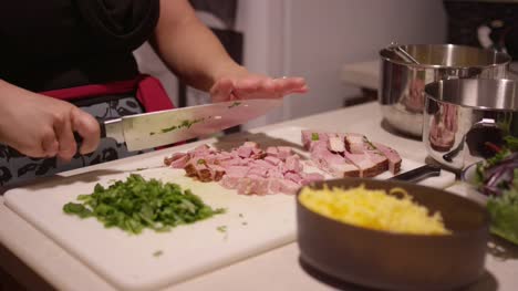 Close-up-of-a-woman-cutting-meat-on-a-cutting-board-in-the-kitchen