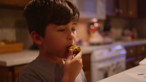 A-little-boy-eating-a-pastry-in-the-kitchen