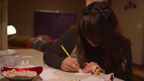 Una-chica-sentada-en-un-mostrador-de-cocina-escribiendo-en-un-trozo-de-papel