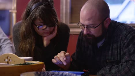 A-father-and-daughter-at-the-table-looking-at-a-tablet-together