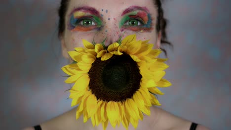 4k-Shot-of-a-Woman-with-Multicoloured-Make-up-With-Sunflower-(focus-on-flower)