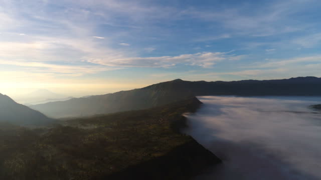 Aerial-view-flight-over-Cemoro-Lawang,-small-village-in-morning-mist.