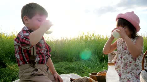Glückliche-Kinder-in-frischer-Luft,-Brot-und-Milchprodukte-essen,-während-im-übrigen-Freunde-auf-grünen-Rasen,-Kinder-bei-Picknick,-Familie-trinkt-Milch
