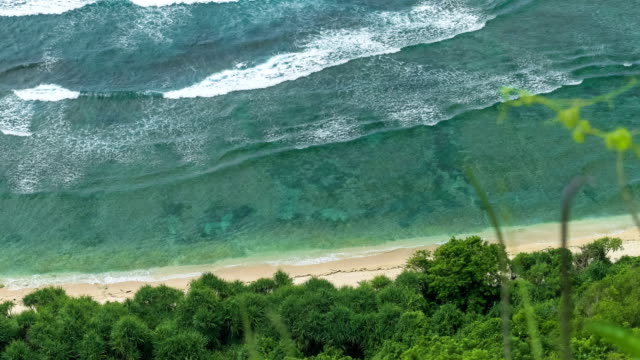 Top-view-perspective-of-waves-rolling-one-by-one-to-the-Nunggalan-Beach,-Uluwatu,-Bali,-Indonesia