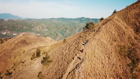 Group-Of-People-Walking-Down-The-Hill-Of-Mount-Batur-Aerial-Shot-4K