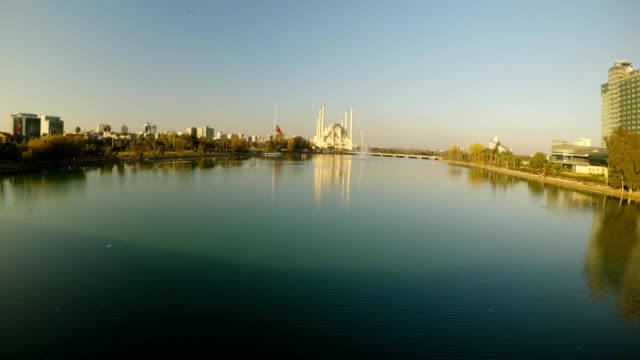 calm-river,-a-mourning-Turkish-flag-and-a-huge-central-city-mosque-in-the-city-of-Adana