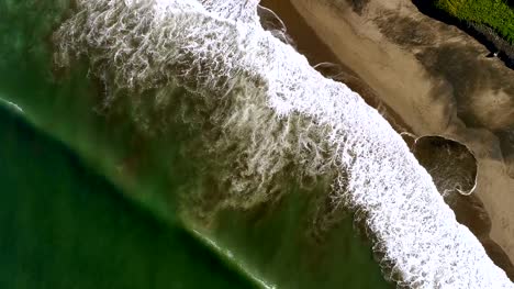 Aerial-view-waves-break-on-white-sand-beach.