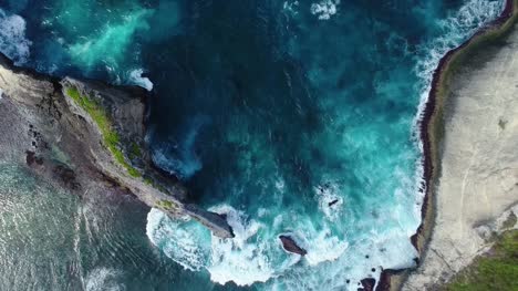 Aerial-view-by-drone-4k-camera.-Rocks-in-a-blue-sea-lagoon-with-breaking-waves.