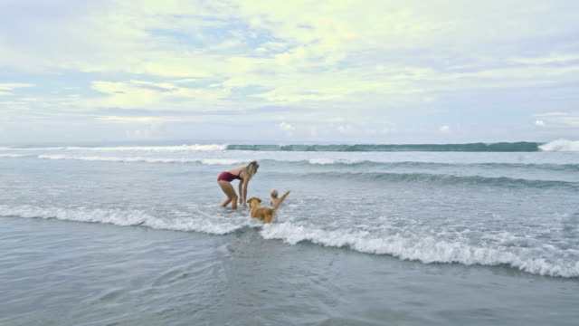 Madre-juega-con-su-hijo-y-perro-en-océano