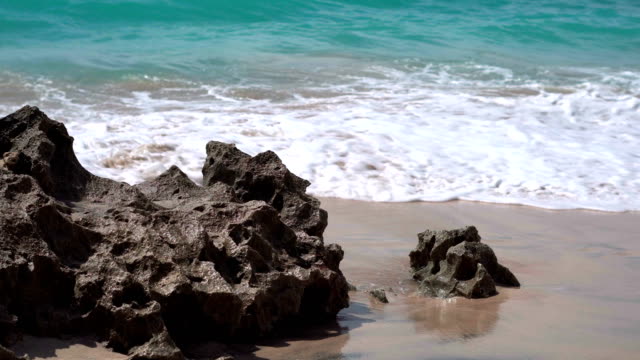 Ocean-foamy-waves-wash-the-coral-rocks-at-sandy-shore