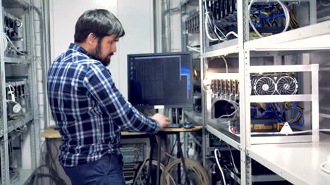 IT-engineer-working-in-cryptocurrency-mining-factory.-Industrial-mining-farm-for-bitcoin-and-cryptocurrency-money.