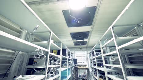 Row-of-bitcoin-miners-set-up-on-the-wired-shelfs.-Mining-cryptocurrency-concept.-Bitcoin-farm.-Machines-for-mining-cryptocurrency,-bitcoin.