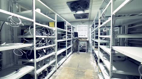 Server-room-for-crypto-currency-mining.-Row-of-bitcoin-miners-set-up-on-the-wired-shelfs.-Mining-cryptocurrency.-Bitcoin-farm.-Machines-for-mining-cryptocurrency,-bitcoin.-Electronic-device-at-day