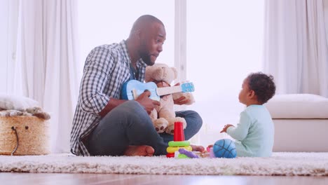 Young-black-father-playing-ukulele-with-son-in-sitting-room