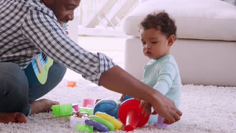 Padre-negro-joven-jugando-con-su-hijo-en-la-sala-de-estar